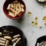 Variety of capsules and pills displayed in bowls on a marble table, ideal for healthcare concepts.