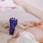 Medical professional taking footprint of a newborn baby in hospital setting.
